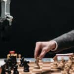 A robotic arm plays chess against a human, symbolizing AI innovation and strategy.