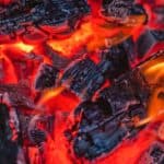 Textured background of charcoal with dry rugged surface burning fast in bright red fire