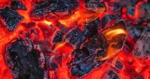 Textured background of charcoal with dry rugged surface burning fast in bright red fire