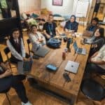 A group of diverse professionals collaborating in a modern office setting with laptops and technology.