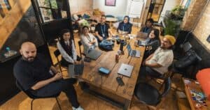 A group of diverse professionals collaborating in a modern office setting with laptops and technology.