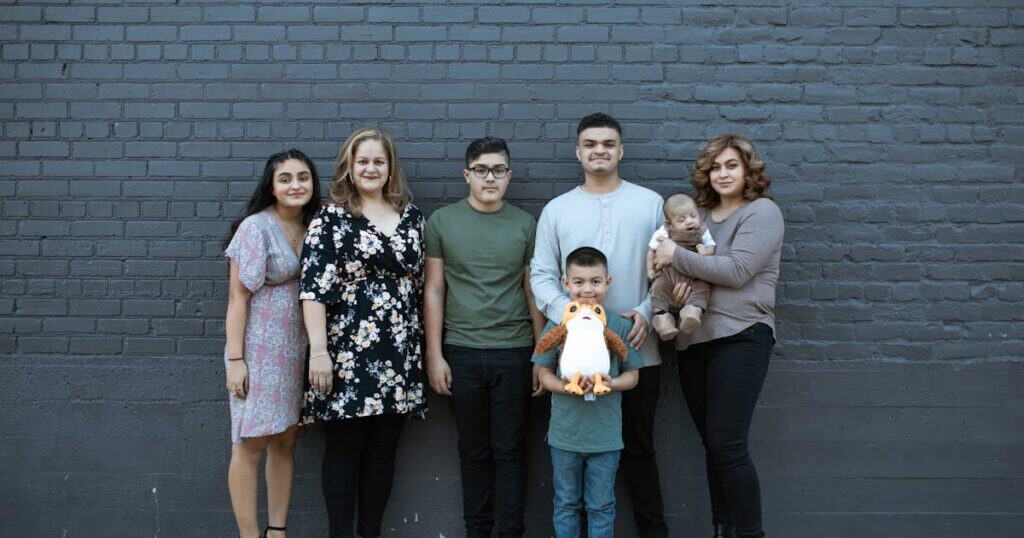 A joyful multigenerational family posing in front of a gray brick wall, symbolizing unity and togetherness.