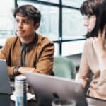 Young professionals collaborate on laptops in a bright, modern office space.