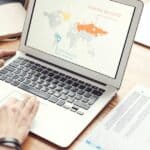 Professional team discussing global marketing strategies with charts and graphs on a laptop.
