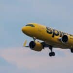 A Spirit Airlines yellow jet in flight over Atlanta, showcasing aviation and travel.